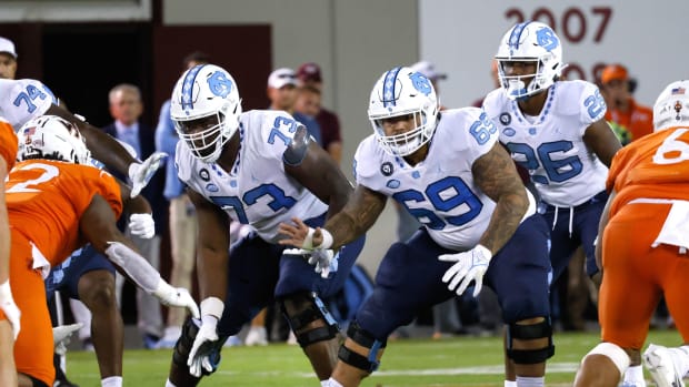 Sep 3, 2021; Blacksburg, Virginia, USA; North Carolina Tar Heels offensive linemen Marcus McKethan (73) and Quiron Johnson (69) and running back D.J. Jones (26) react to the snap during the second half against the Virginia Tech Hokies at Lane Stadium.